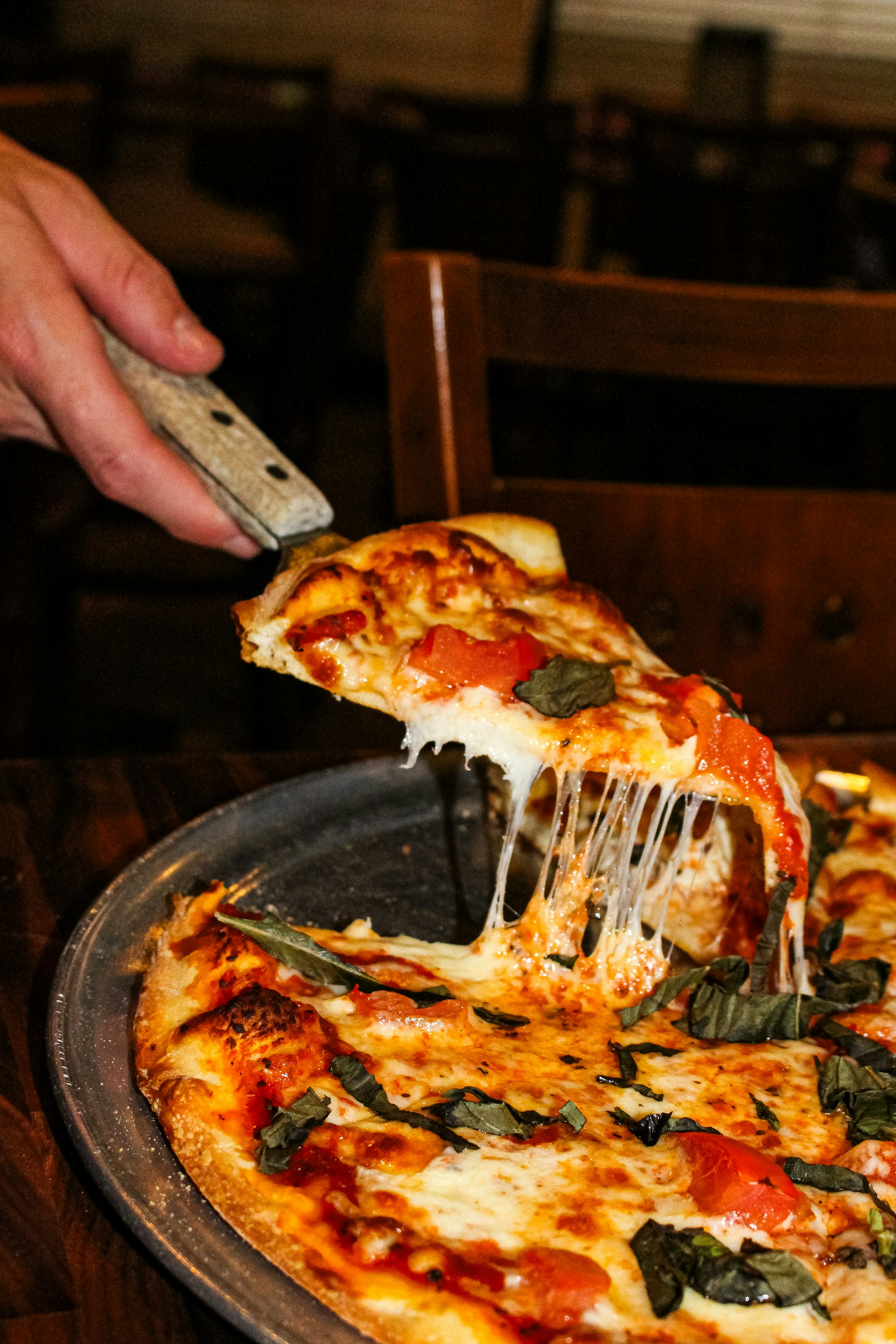 Pizza italiana real com uma fatia sendo retirada e queijo derretendo